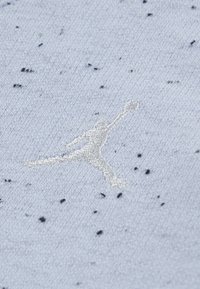 Tejido azul claro con textura salpicada presenta un logo Jumpman bordado en blanco. Diseño simple sin patrones o acentos adicionales.