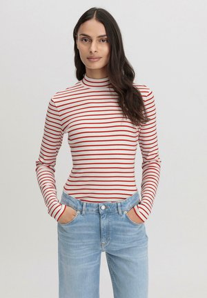 Rood-witte gestreepte coltrui met lange mouwen, gecombineerd met lichtblauwe spijkerbroek. De stof lijkt zacht en heeft een aansluitend ontwerp.