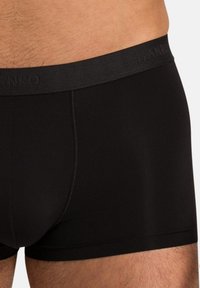 Black boxer briefs made of smooth fabric, featuring a soft elastic waistband with embossed brand name and flatlock stitching details.