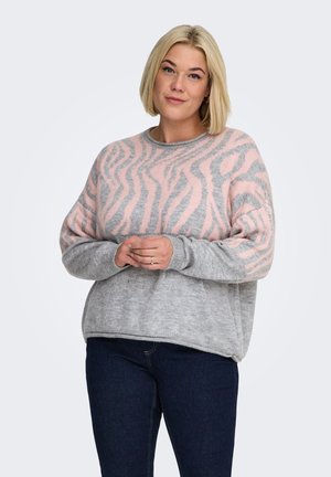 Suéter gris tejido con un patrón de rayas de cebra rosa, cuello redondo y mangas largas, combinado con jeans oscuros.