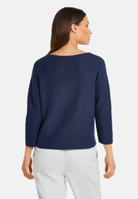 Marineblauer Pullover mit tiefem Rückenausschnitt, Dreiviertelärmeln und strukturierten Oberflächen. Einfaches, gerades Design ohne sichtbare Verzierungen.