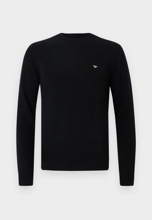 Black knitted sweater with a round neckline, long sleeves, and a small golden logo accent on the chest. Smooth texture. Classic fit.