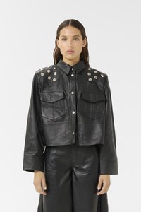 Zwarte leren cropped jack met twee voorzakken, knoopsluiting en zilverkleurige studs op de schouders. Gladde textuur.