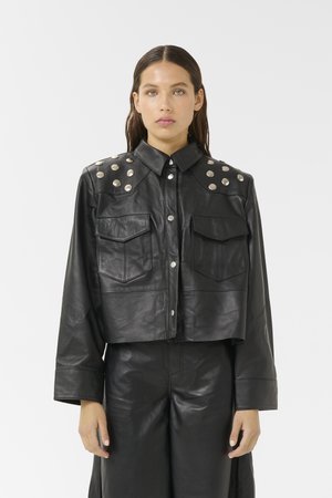 Black leather cropped jacket with two front pockets, button closure, and silver studded accents on the shoulders. Smooth texture.