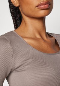 Geribbelde, kortmouw top in muted taupe, met een brede halslijn en een gladde textuur, die de rek en pasvorm van de stof accentueert.