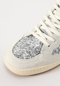 Sneaker con una toma grigia chiara in suede, dettagli in glitter argento sulla punta, lacci crema e suola in gomma testurizzata bianco sporco.