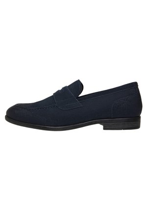Mocassini in suede blu navy con cucitura, punta rotonda e suola in gomma nera piatta. Presenta una linguetta decorativa frontale.