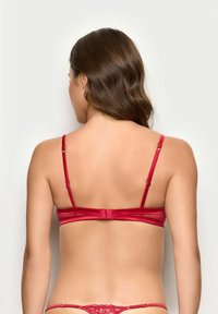 Czerwony satynowy biustonosz z regulowanymi ramiączkami, posiadający gładką powierzchnię i zapięcie z tyłu. Minimalistyczny design bez widocznych wzorów.