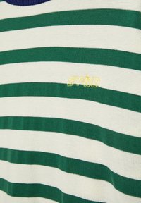 Tessuto a righe orizzontali verdi e bianche con piccolo testo giallo ricamato "STÜND" vicino al centro.