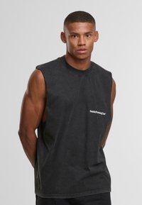 T-shirt nera senza maniche in cotone con collo a giro. Presenta un logo bianco sul petto e una vestibilità comoda. Texture opaca.