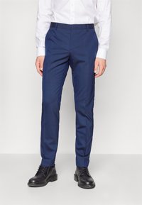 Navy blue trousers made from a smooth fabric, featuring a tailored fit, side pockets, and a flat front design. Worn with black leather shoes.