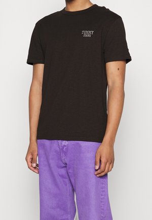 T-shirt en coton marron avec un col rond et des manches courtes, arborant un petit logo blanc "TOMMY JEANS" sur la partie gauche de la poitrine.