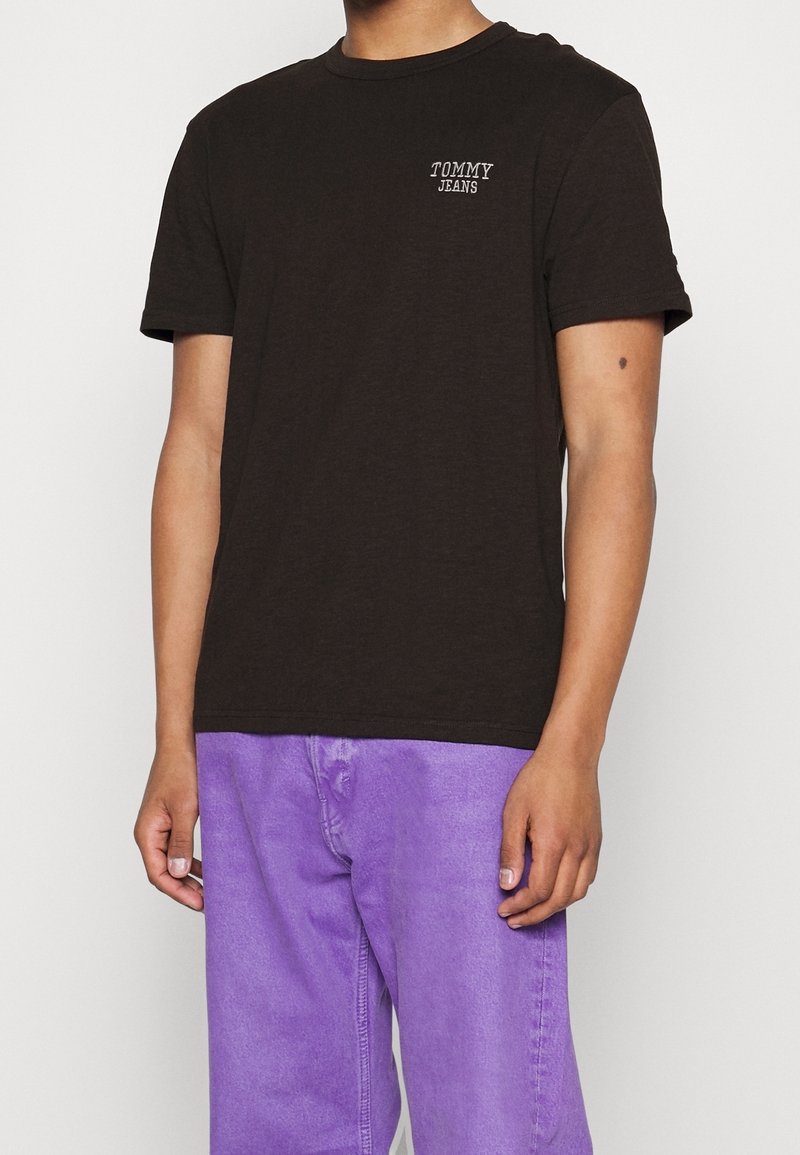 T-shirt en coton marron avec un col rond et des manches courtes, arborant un petit logo blanc "TOMMY JEANS" sur la partie gauche de la poitrine.