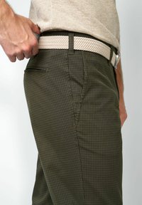 Olivgrüne karierte Hose mit strukturierter Oberfläche und hellem geflochtenem Gürtel. Mit Seitentaschen und schlank geschnittenem Design.