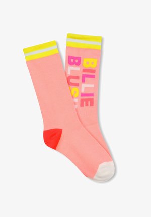 Chaussettes roses avec des poignets rayés jaunes et blancs, présentant un texte coloré "BILLIE BLUSH" dans différentes couleurs et un détail de talon rouge contrastant.