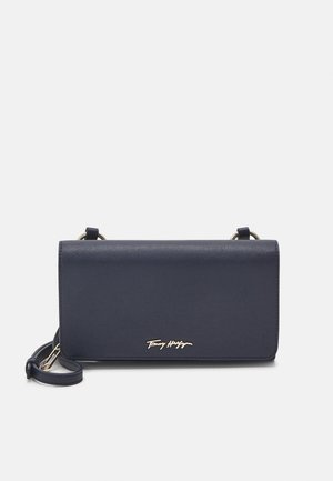 Sac bandoulière en cuir synthétique bleu marine avec rabat pliant, détail signature doré et sangle amovible. Texture lisse et forme rectangulaire.