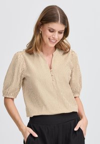 Stribet, kortærmet bluse i beige og creme med en henley-udskæring og tre knapper. Blødt stof med en let struktureret overflade.
