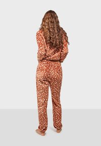 Brown polka dot pajama set in soft fabric, featuring a long-sleeve top and matching pants with an elastic waistband.