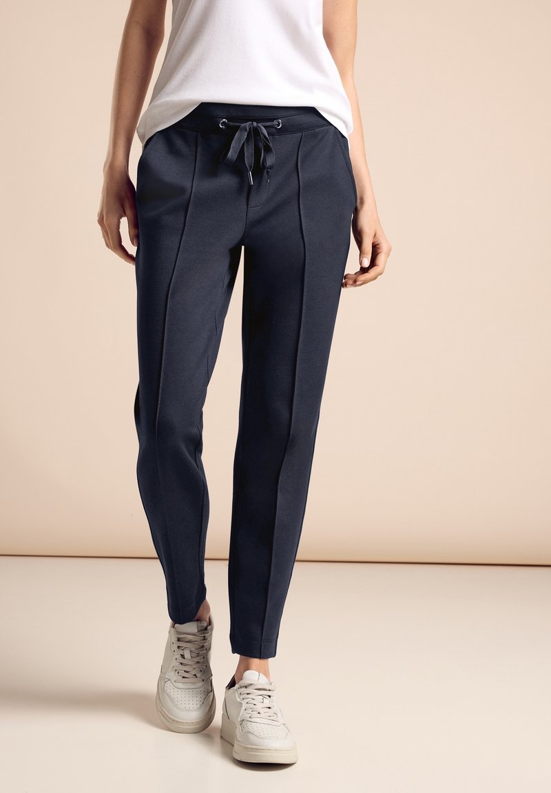 Marina joggerbyxor i mjukt tyg, med dragsko i midjan, sidopaneler och en avsmalnande bendesign. Kombineras med vita sneakers.