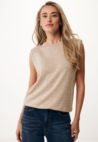 Top beige senza maniche realizzato in morbido tessuto jersey, con scollatura rotonda e vestibilità ampia, abbinato a jeans blu scuro.
