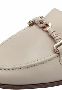 Mocassino in pelle beige con accento a catena in tono dorato. Presenta una punta arrotondata e cuciture a contrasto lungo il bordo. Texture liscia.