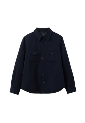 Camisa negra de manga larga con botones, cuello puntiagudo y dos bolsillos frontales con solapa, presentada sobre un fondo blanco.