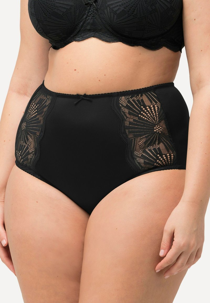 Hoge taille zwarte panties met gedetailleerde kanten zijpanelen, een gegolfde rand en een kleine strikaccent bij de taille. Vlotte stofstructuur.