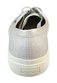 Sølvfarvet stofsneaker med tekstureret overflade, hvid gummisål og snørelukning. Har en logo på hælen og lavt design.