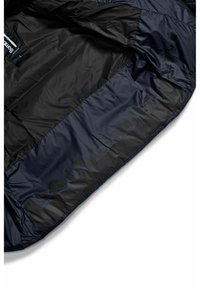 Interno della giacca puffer blu navy con una texture liscia e lucida. Presenta una grande stampa del logo nero e simboli di cura sul lato.