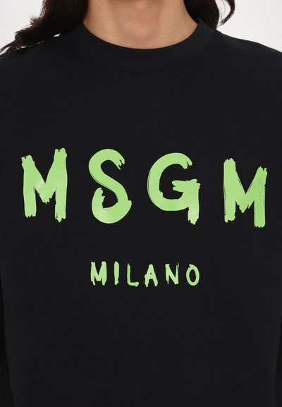 Zwarte sweatshirt met grote, textuurrijke neon groene letters "MSGM" en "MILANO" in een gedurfde, schilderachtige stijl.