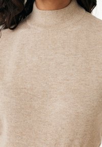 Beige turtleneck sweater with a soft, textured fabric. Features a high collar and a smooth knit design. Lightweight and fitted.