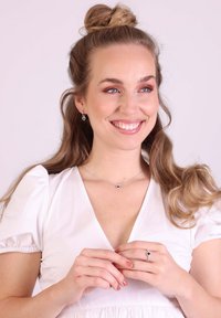 Joyería de plata con un colgante de piedra azul en forma de corazón sobre una delicada cadena, complementada por unos pendientes y un anillo a juego.