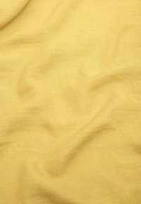 Tissu en lin jaune doux et texturé avec une apparence légèrement froissée, présentant une couleur chaude et atténuée ainsi qu'un tissage en fibres naturelles.