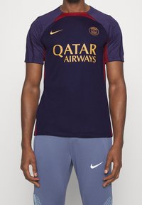 Camisa de fútbol de Nike en azul marino oscuro con acentos en burdeos. Presenta el logo de QATAR AIRWAYS en dorado. Manga corta con diseño texturizado en los hombros.