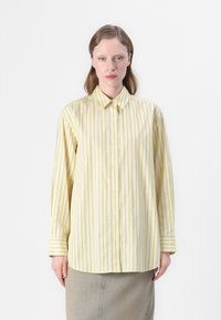 Camicia gialla a maniche lunghe con righe verticali viola, frontale con bottoni e colletto classico. Il tessuto appare liscio con una leggera lucentezza.