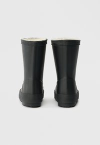 Botas de chuva pretas de borracha com um exterior liso, solas texturizadas e um forro de pêlo branco na parte superior. Apresentam um design curto clássico.