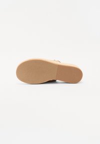 Sandal såle laget av teksturert beige gummi med en avrundet form; har subtile riller for grep og en litt hevet hel.