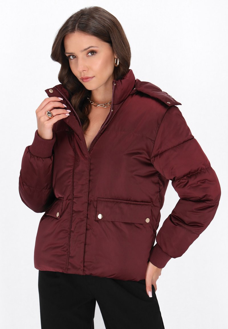 Giacca imbottita bordeaux con bottoni a pressione, colletto alto, due tasche anteriori, polsini a coste e texture trapuntata.