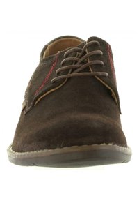 Chaussure à lacets en daim marron avec des détails de couture rouge, un bout arrondi et une semelle en caoutchouc lisse. Le design présente des accents minimalistes.