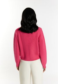 Maglione lavorato a maglia fucsia con un motivo testurizzato, maniche lunghe e una vestibilità corta. Il retro presenta un design semplice senza ulteriori dettagli.