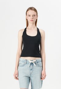 Black cropped tank top with a scoop neckline, made of soft fabric. Worn with light blue high-waisted denim shorts featuring a drawstring.
