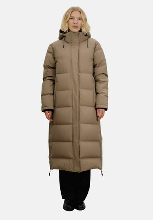 Vattert lang parka i beige, med høy krage og hette, med quiltede seksjoner og glidelåsdetaljer, paret med svarte bukser og sko.