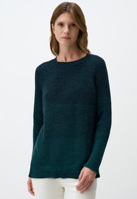 Donkerblauwe gebreide trui met een ronde hals, lange mouwen en ribbels aan de onderkant. De textuur is grof en gezellig, perfect voor casual kleding.