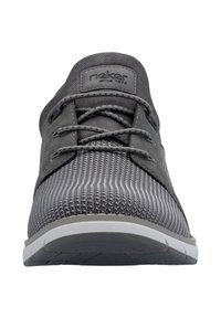 Baskets de sport grises avec une tige en tricot texturé, des lacets ton sur ton et une semelle gris clair, avec une étiquette portant la mention "rieker depuis 1874" sur la languette.