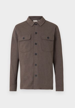 Bruine lange-mouw blouse met knopen, voorzien van twee borstzakken met knopen en een klassieke kraag, op een witte achtergrond.