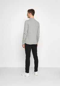 Light gray long-sleeve shirt with a round neck, smooth texture, slim fit, paired with black slim-fit pants and white sneakers.