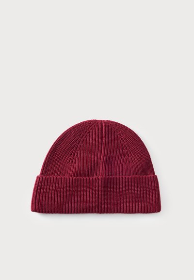 Bonnet tricoté couleur bordeaux avec un revers côtelé, présenté sur un fond clair uni.