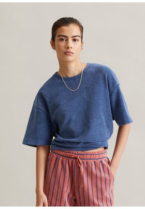 Chemise bleu en éponge à manches courtes, associée à un pantalon rayé rose. Caractéristiques : coupe décontractée et encolure ronde, avec des détails de couture visibles.