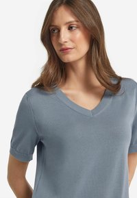 Ljusblå, kortärmad V-ringad tröja i ett mjukt material. Har fint sydda sömmar och en avslappnad passform.