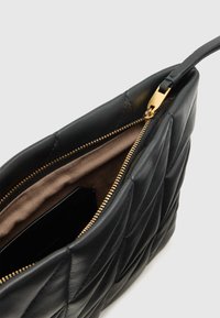 Juodos odos rankinė su siuvinėtu raštu, auksinio atspalvio užtrauktuku ir smėlinio spalvos pamušalu. Turi vieną petnešą ir erdvų vidų.